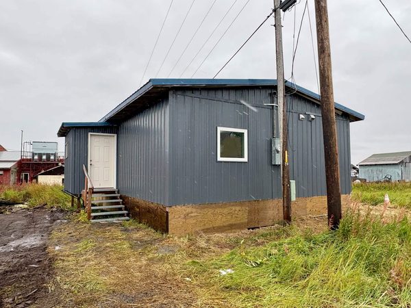 Gray metal-sided home with a white entry door, a window and wooden entry stairs