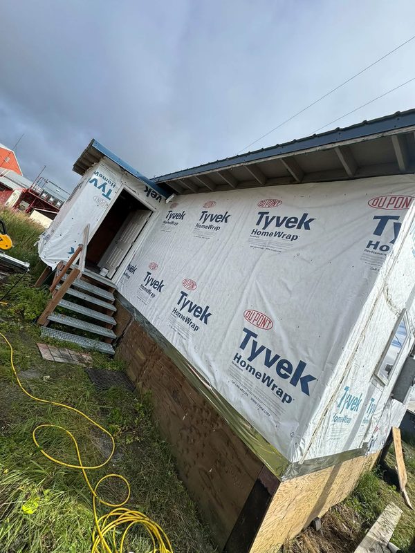 Exterior walls of a home covered in house wrap, with metal entry stairs