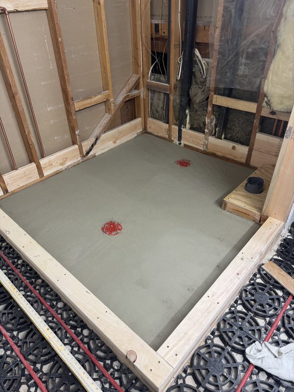 Shower pan mortar bed inside framed walls, with heating panels on the floor around it